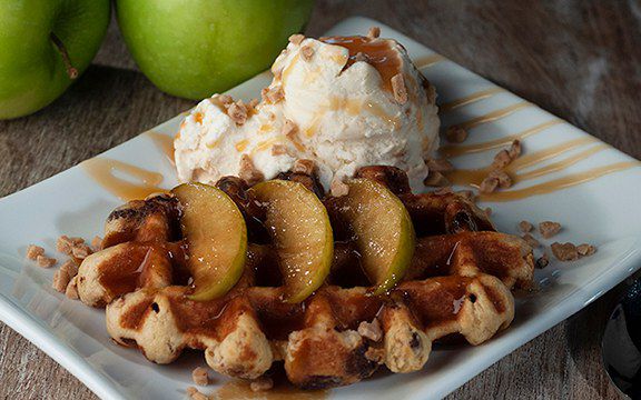 Liège waffle topped with caramelized apple slices, ice cream, toffee bits and caramel drizzle