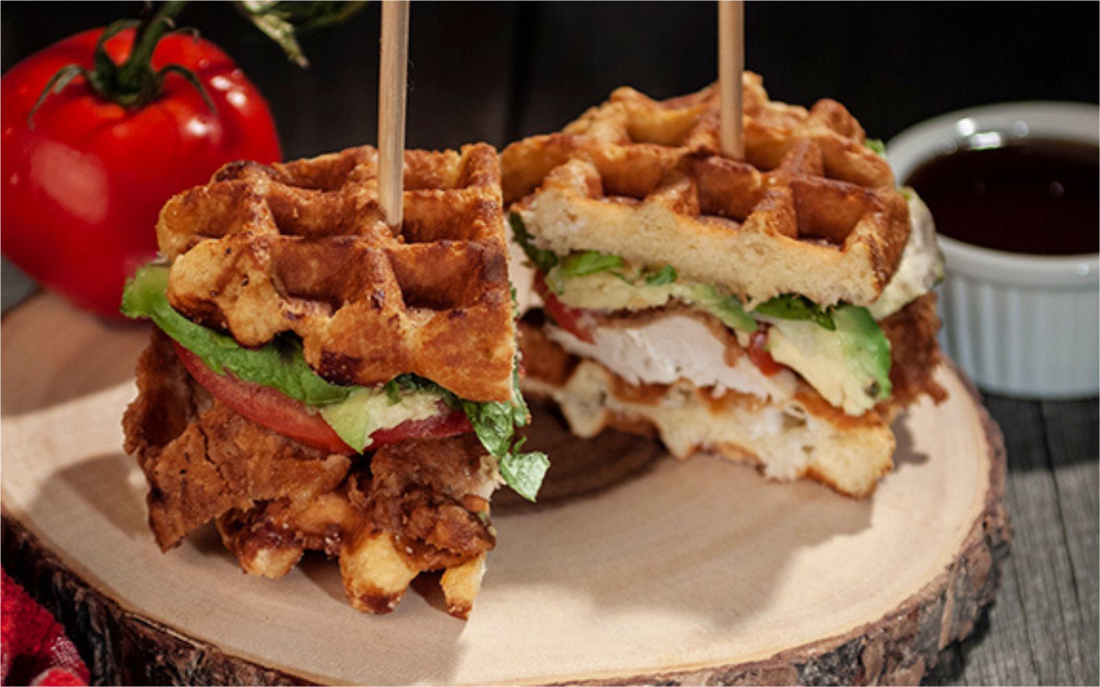 Crispy chicken, avocado, lettuce and tomato on Liège waffles, cut in half, with a cup of dipping sauce